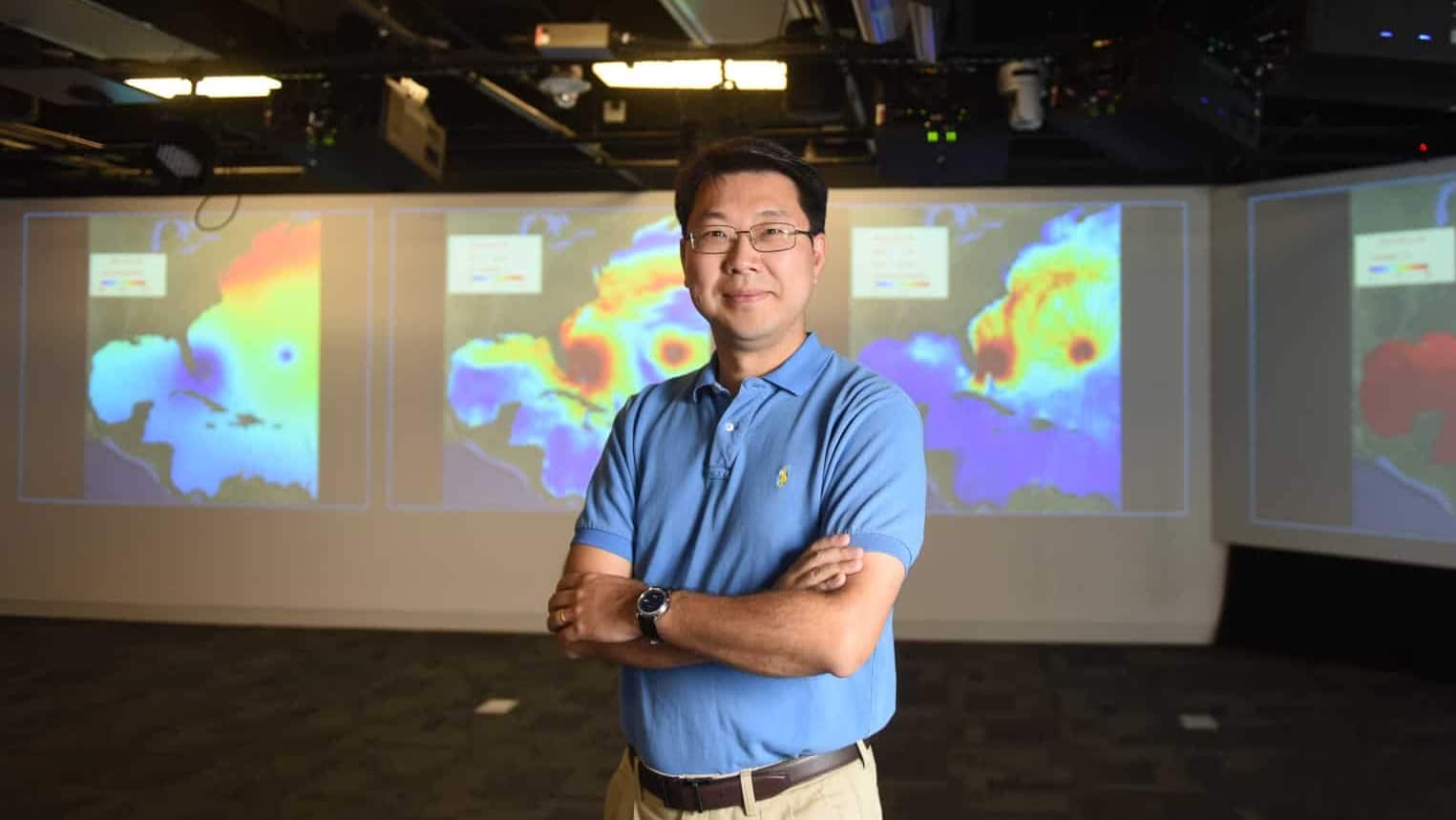 Ruoying He in front of a screen displaying ocean weather visualizations