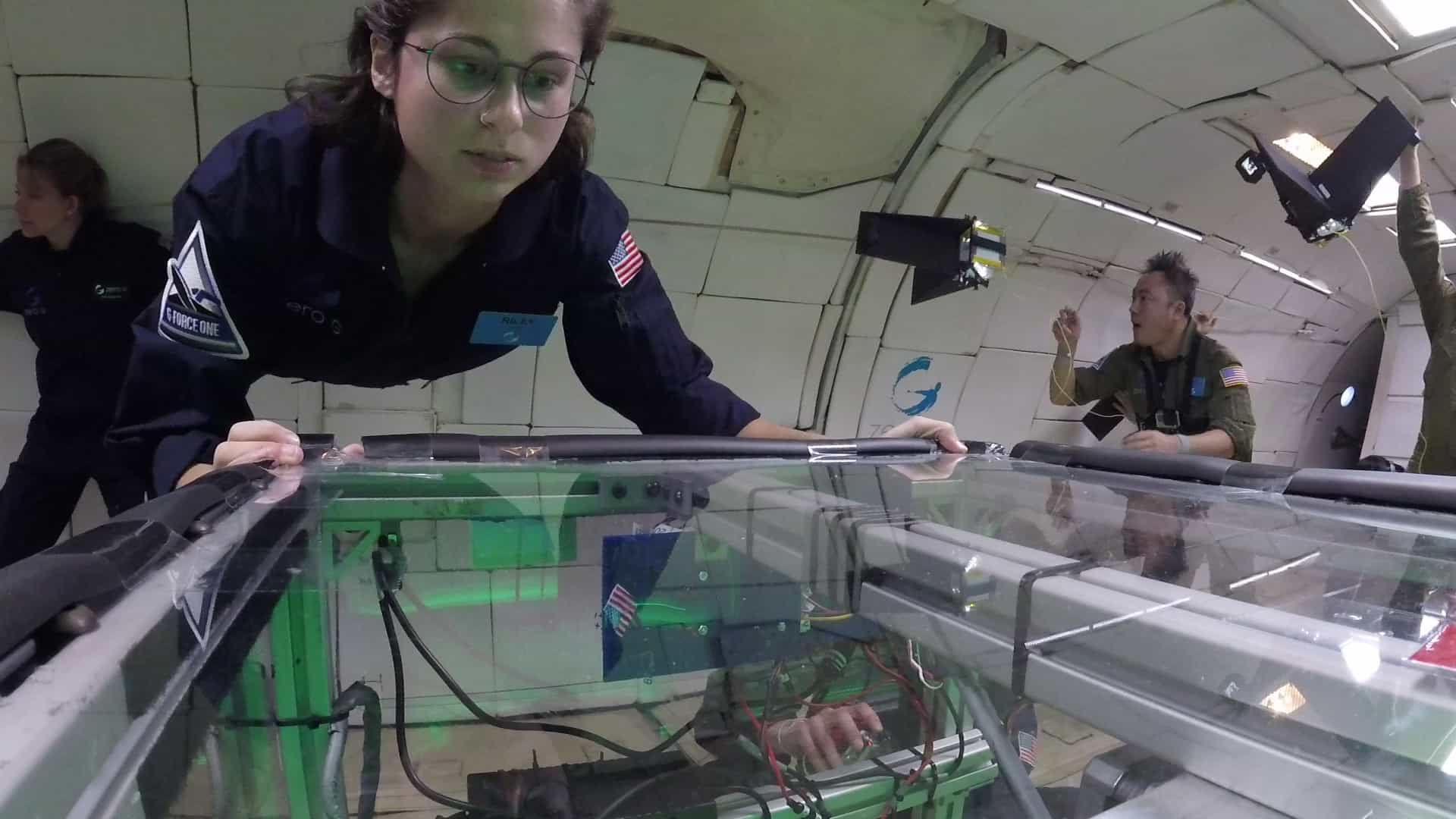 A student floats above an experimental apparatus onboard a zero-gravity research flight