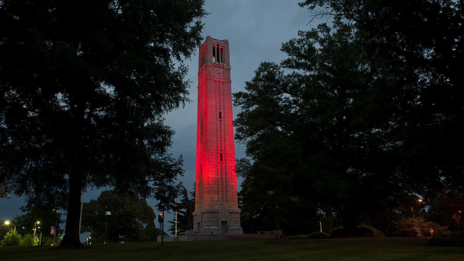 The NC State Belltower lit red against a night sky