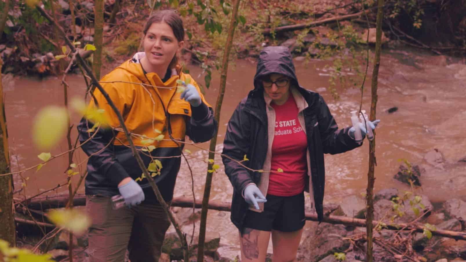 Carli Arendt and a graduate student stand on the banks of a stream