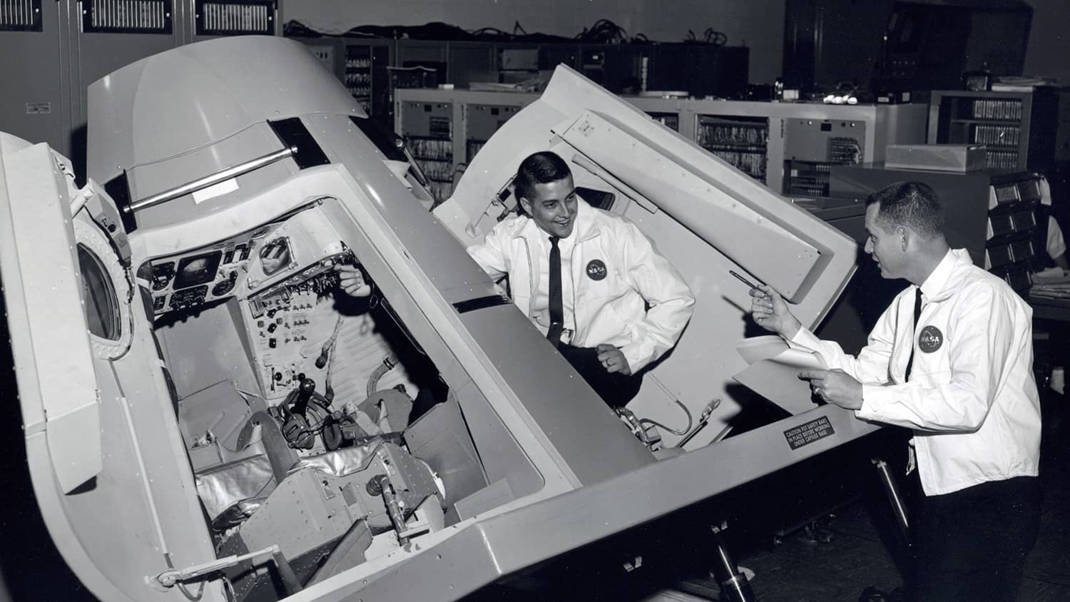 Jim Prim and George Prude pose in the Gemini Trainer used in the Apollo 11 mission.