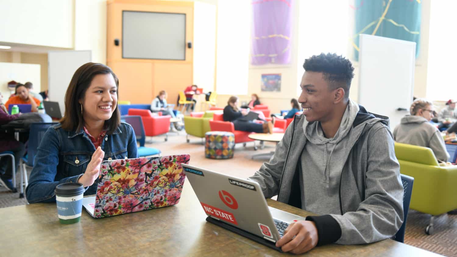 Two students work on laptops in the Riddick Hall Hearth