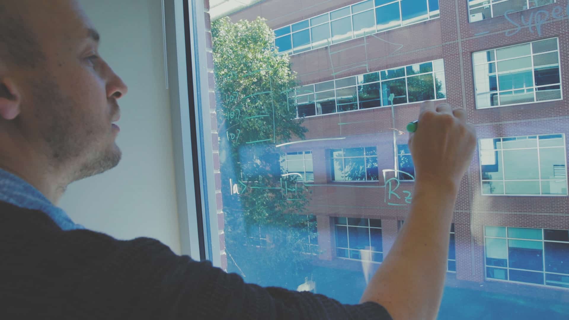 Lex Kemper working out physics equations on a glass window in his office