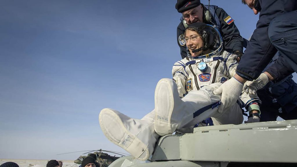 Christina Koch is helped out of a landing capsule on Earth