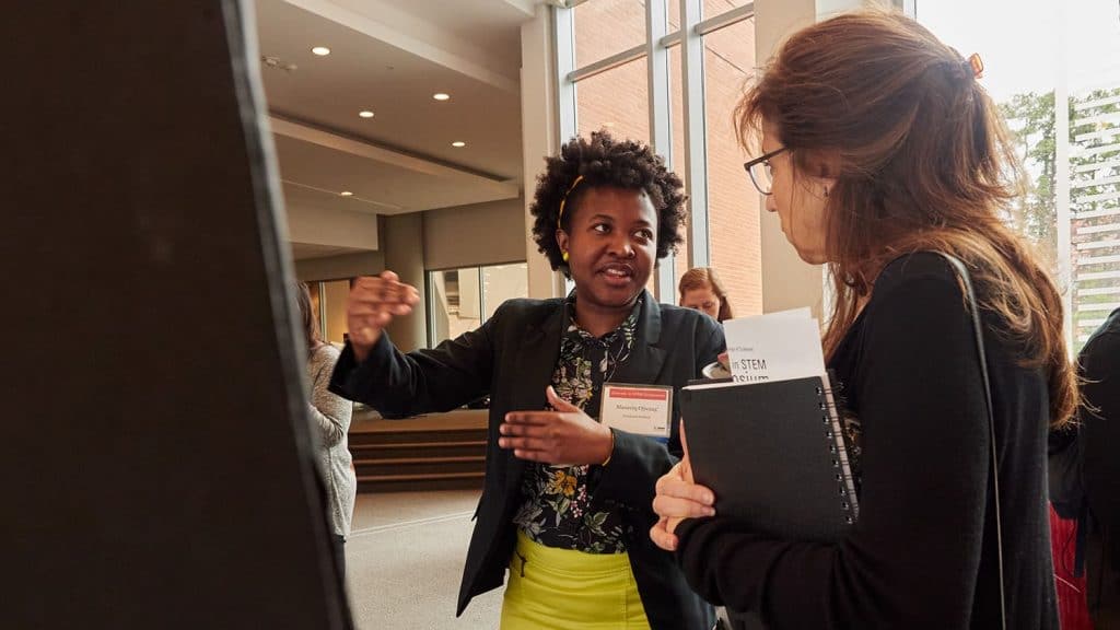 Ph.D. student Maureiq Ojwang' explains her research poster to an attendee.