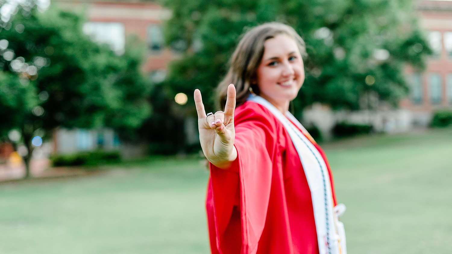 Natalie Truby in graduation robe, holding up wolf hands