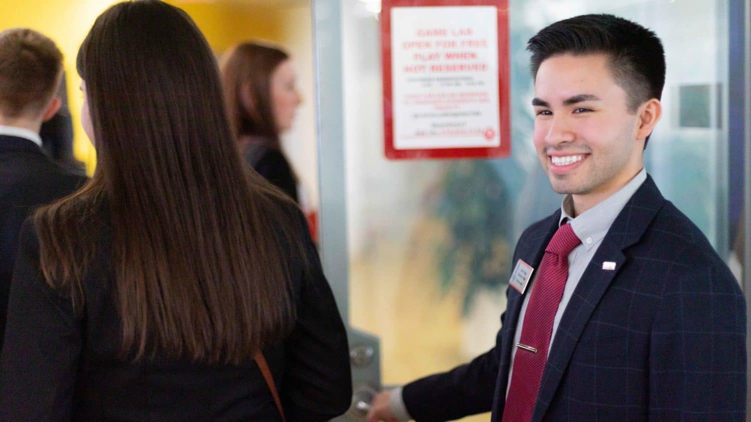 Alex Rojas smiles as he holds a door