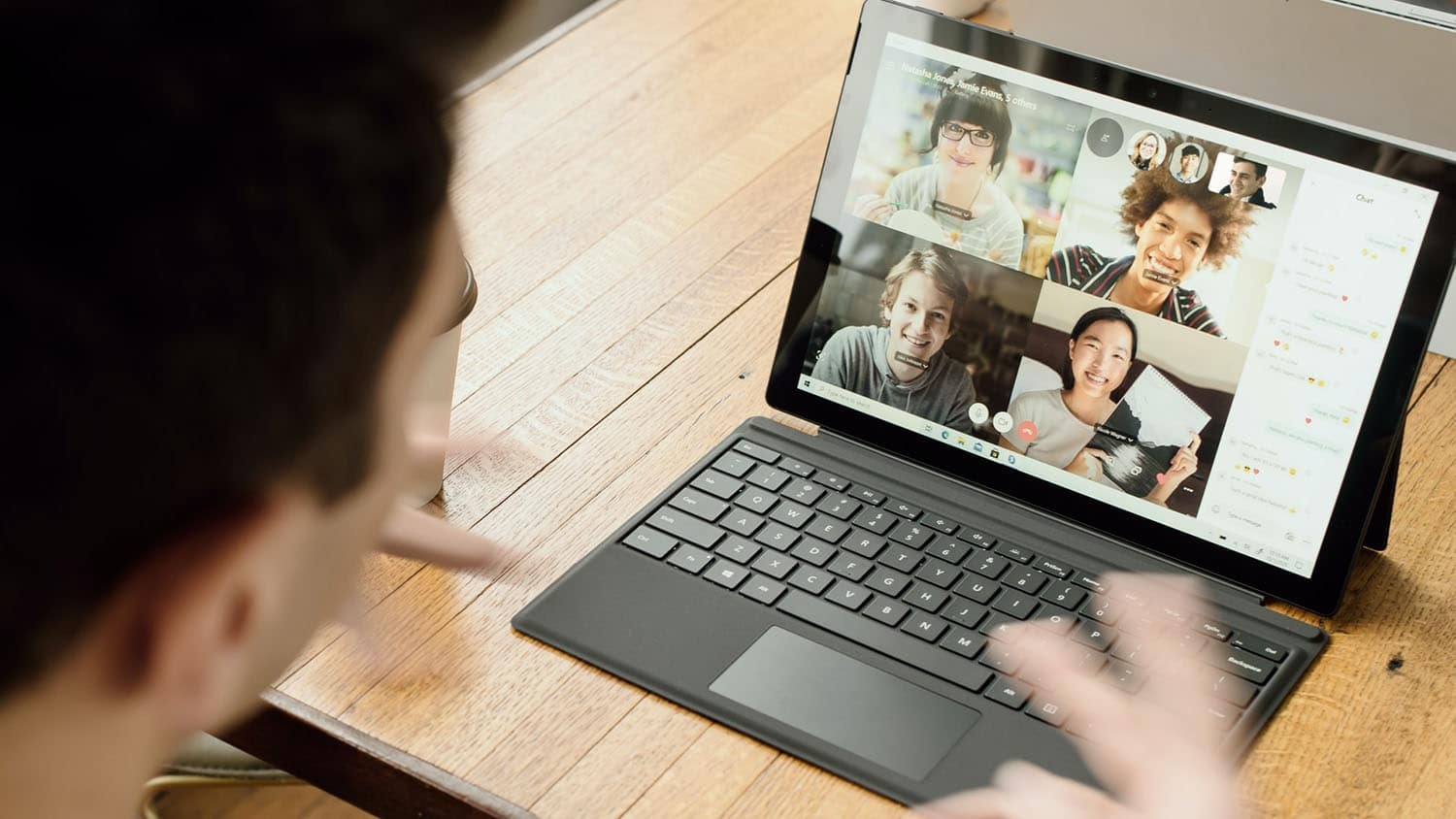 a person is engaged in a video conference with several other people who are pictured on the screen of a laptop