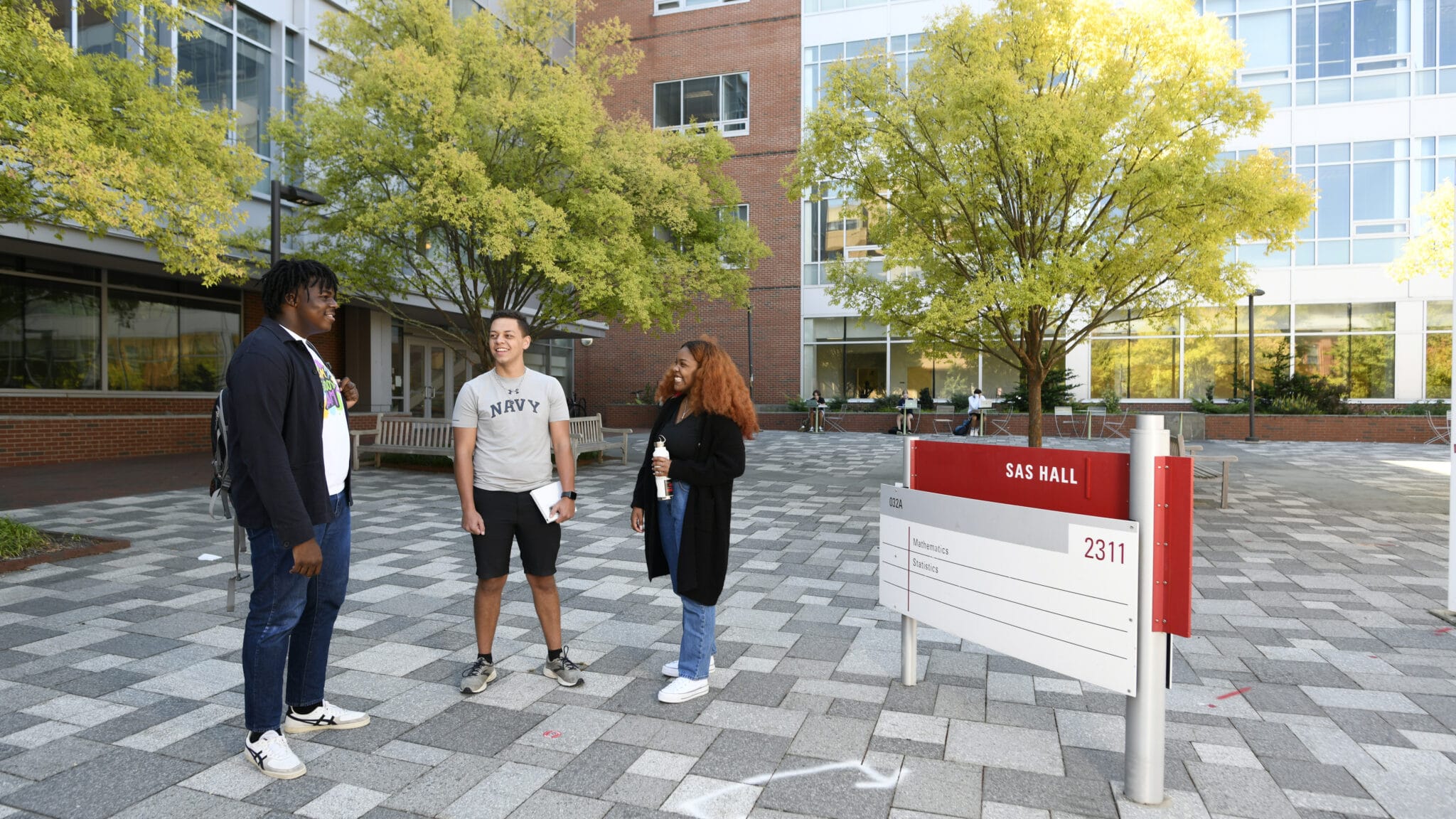 Three students talk outside SAS Hall