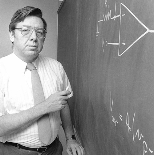 A black-and-white photo of Kenneth Hanck at a chalkboard in a classroom