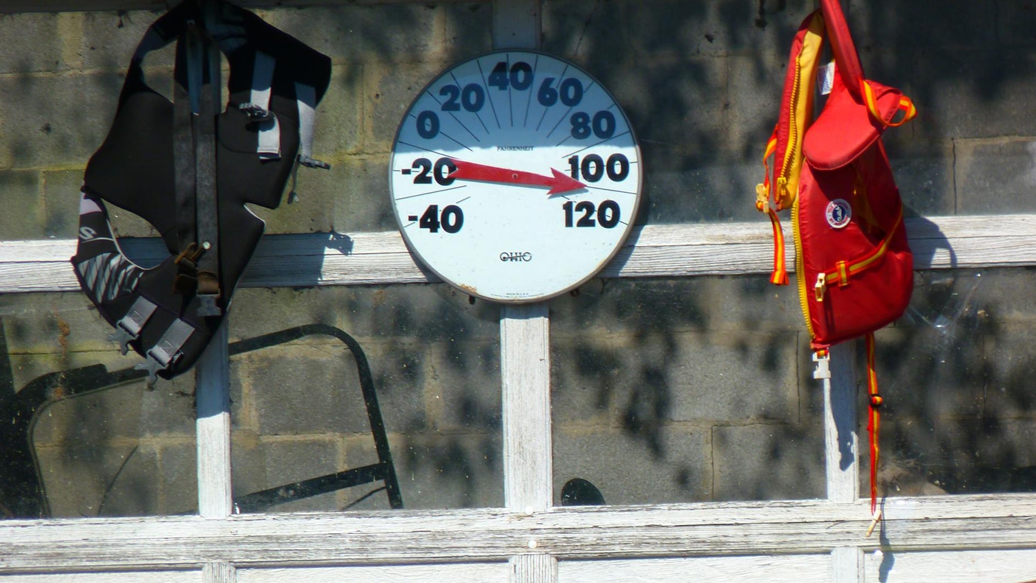 A round temperature gauge and other tools hang on a wall