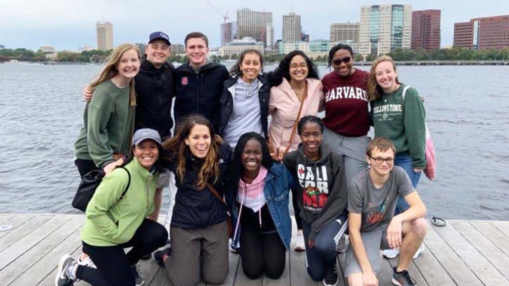 A group of students in front of a Boston skyline. 