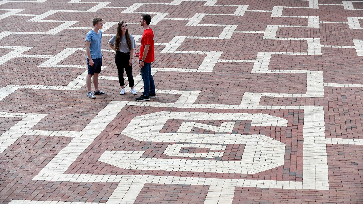 Three students talk in the Brickyard.