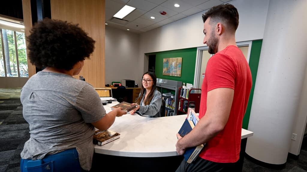 Two students check out books at the Natural Resources Library