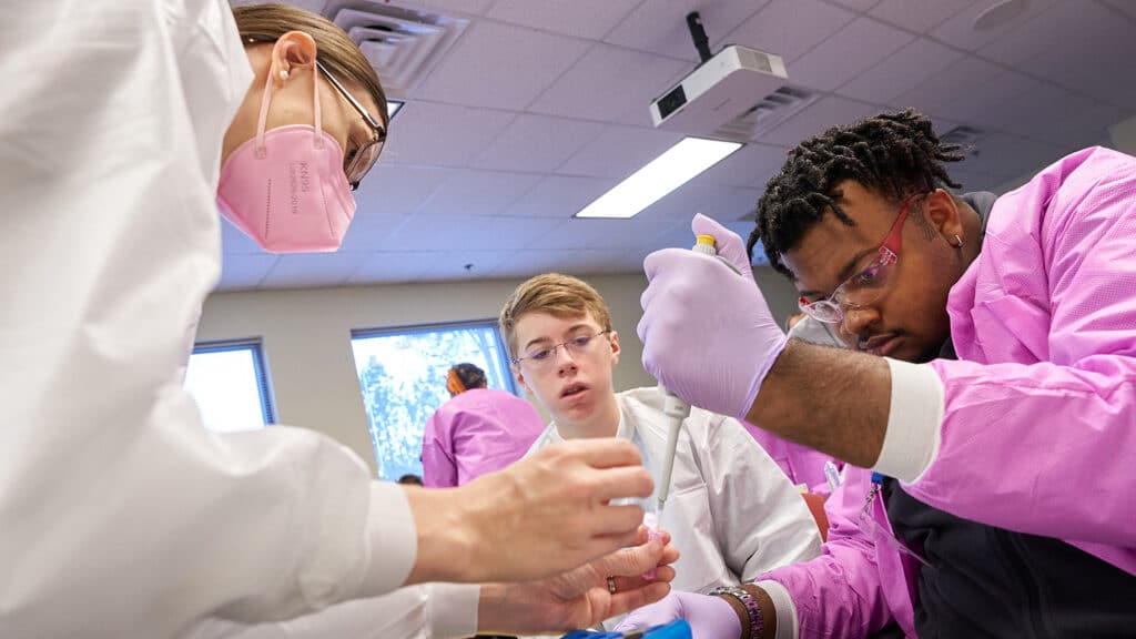 An NC State faculty members helps Catalyst students with a lab activity