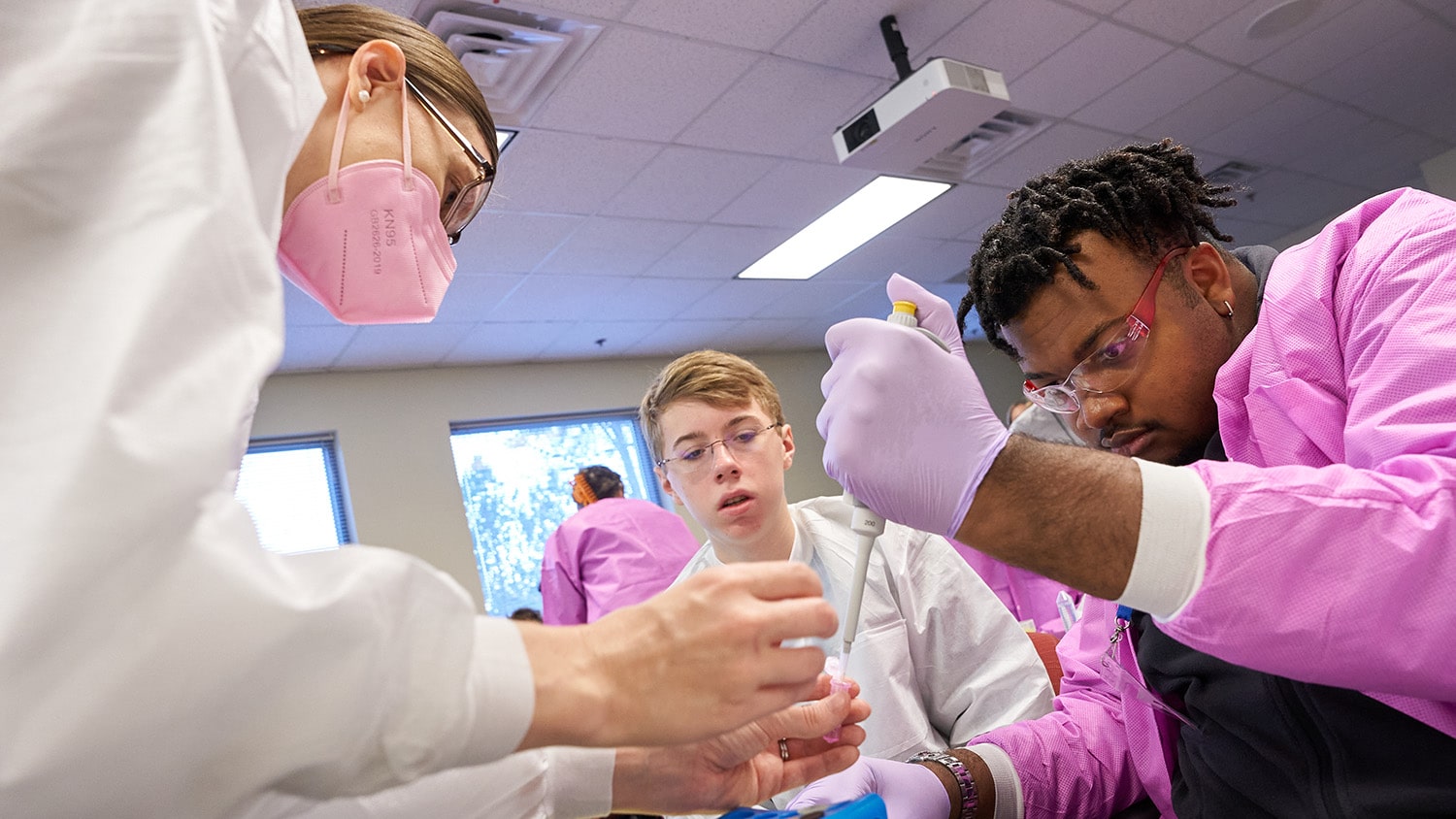 An NC State faculty member helps Catalyst students with a lab activity