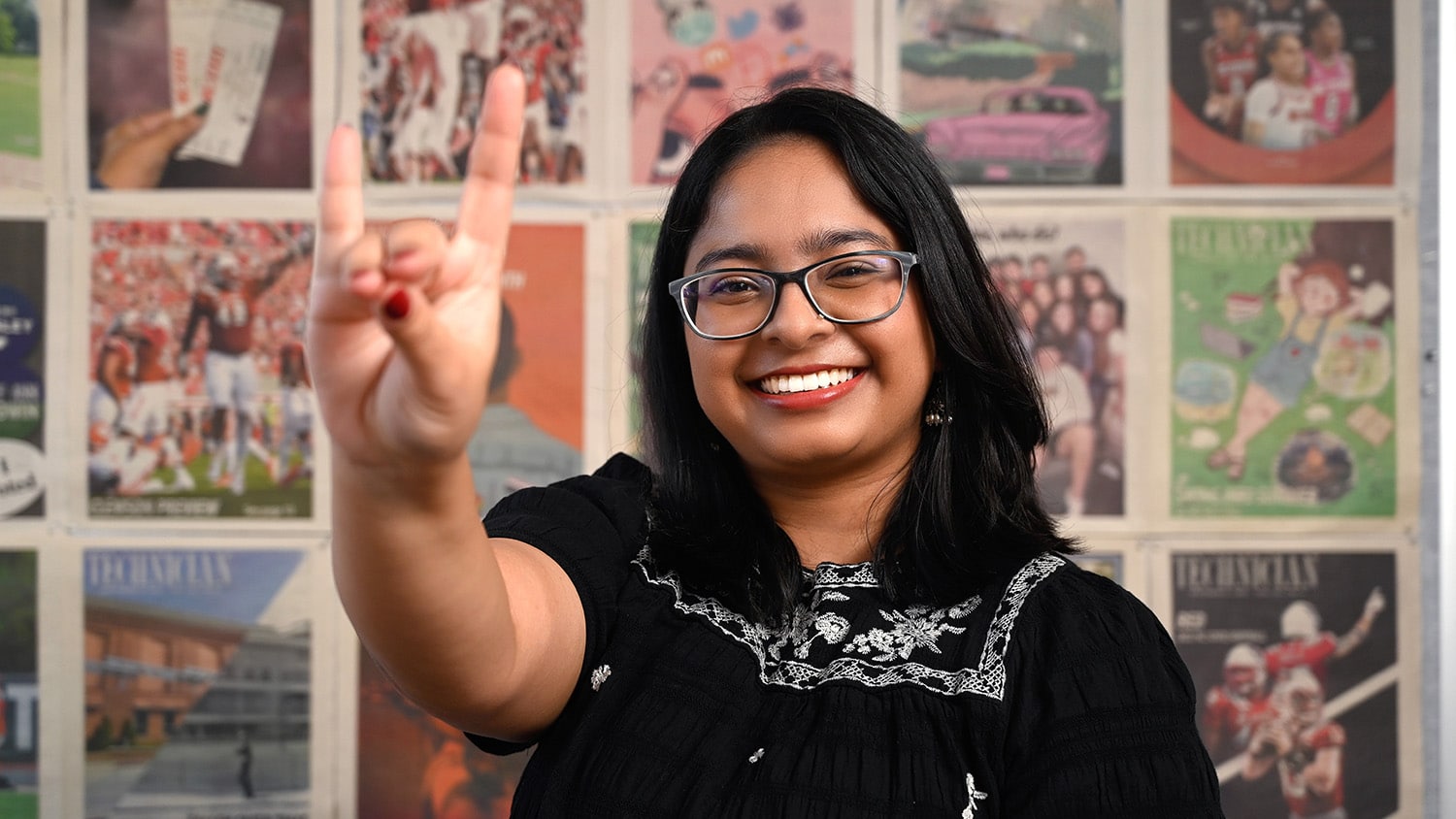 Biological sciences student Shilpa Giri smiles in front of a wall covered in issues of Technician