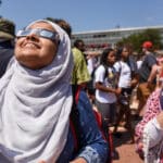 Students view the 2017 solar eclipse from the Brickyard with sun-safe glasses.