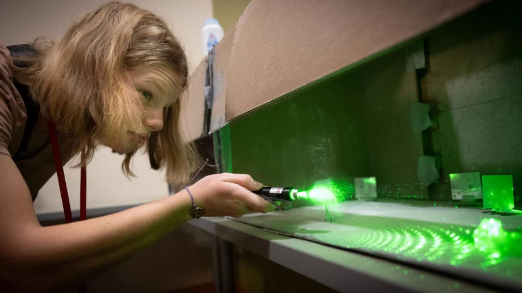 A student shines a green light over a tabletop surface