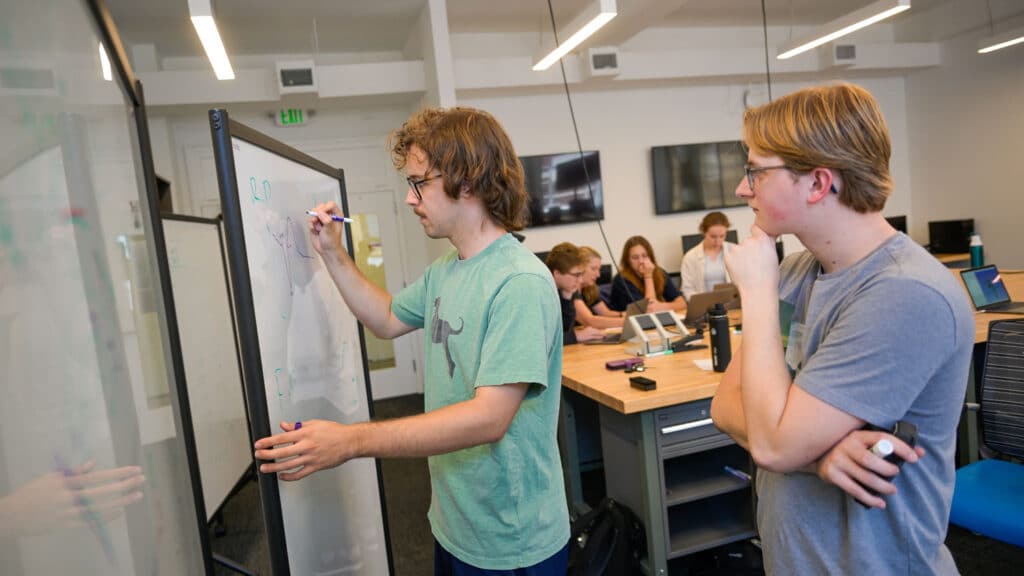 Ian Kriel and a teammate work out a math problem on a whiteboard