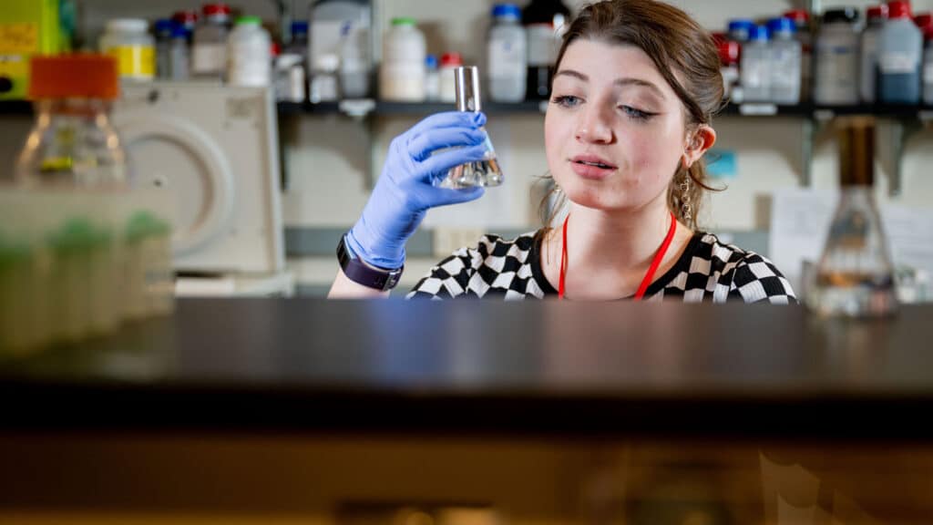 Kaelyn Coates holds a beaker filled with liquid