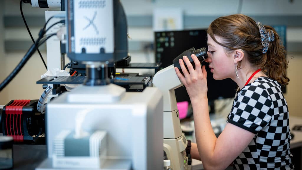 Kaelyn Coates looks into a microscope