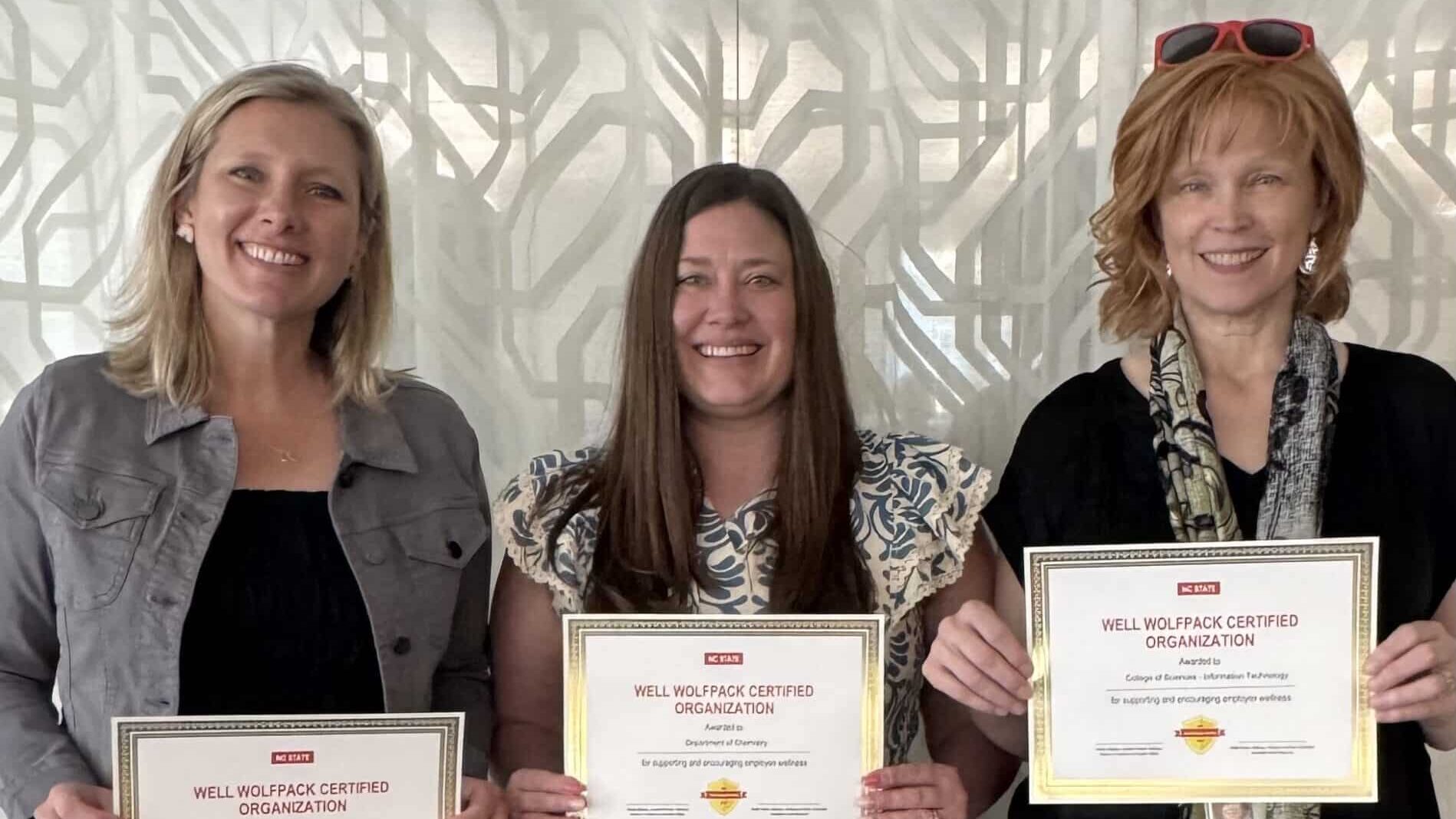 Three people holding certificates looking at the camera