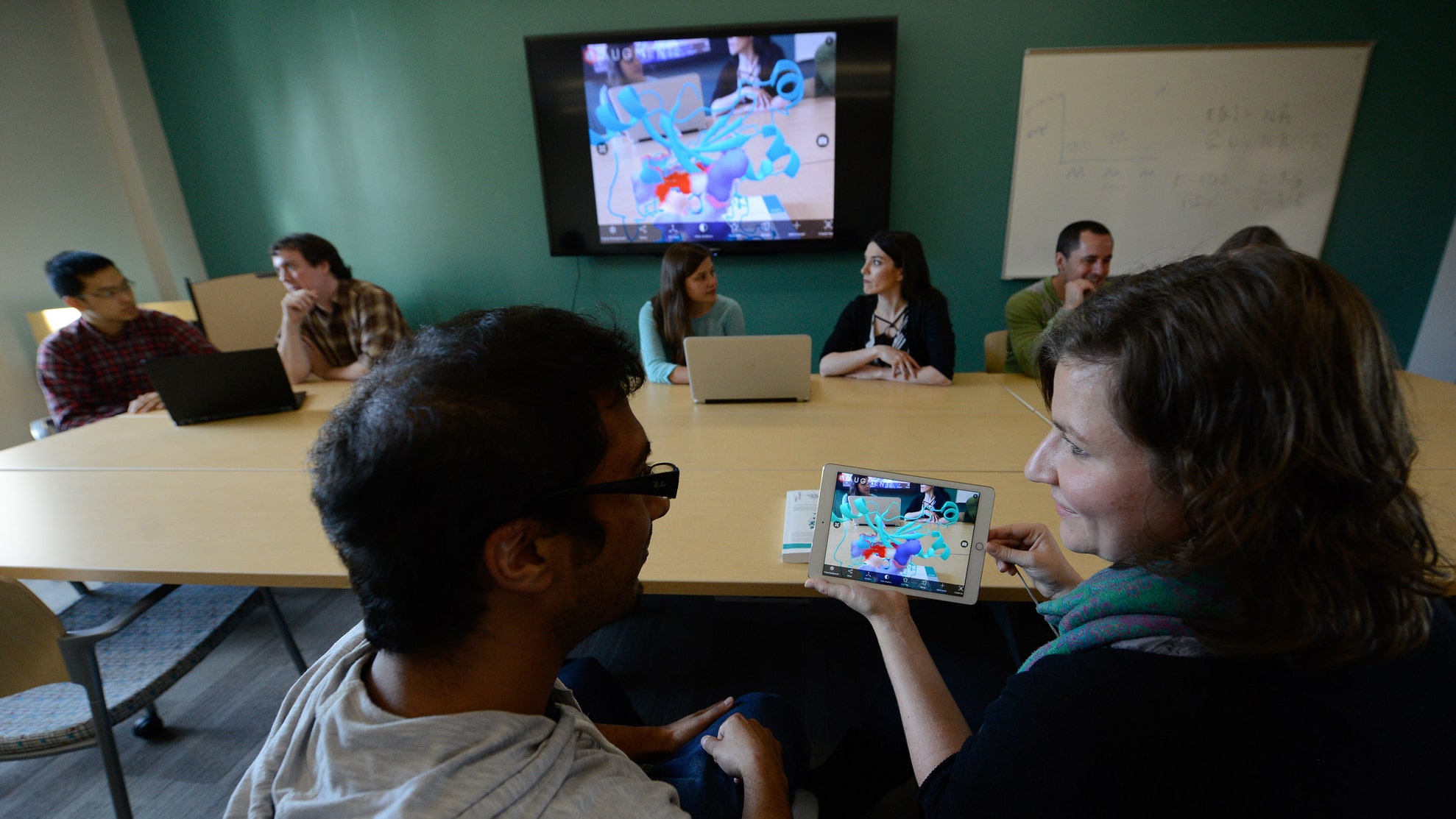 Graduate students collaborating while looking at iPad with molecular structure displayed