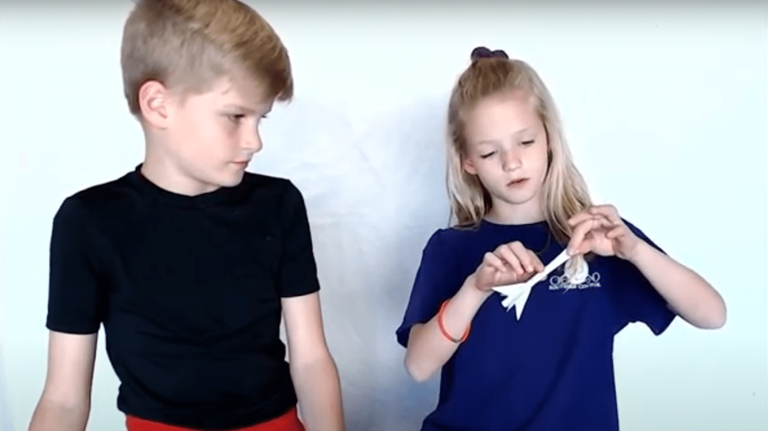 Two kids work on building a straw rocket
