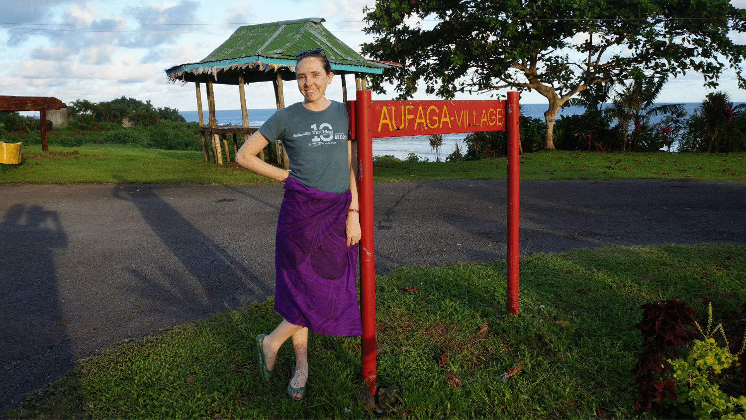 Natalie Ziemba stands in front of a sign that reads Aufaga Village
