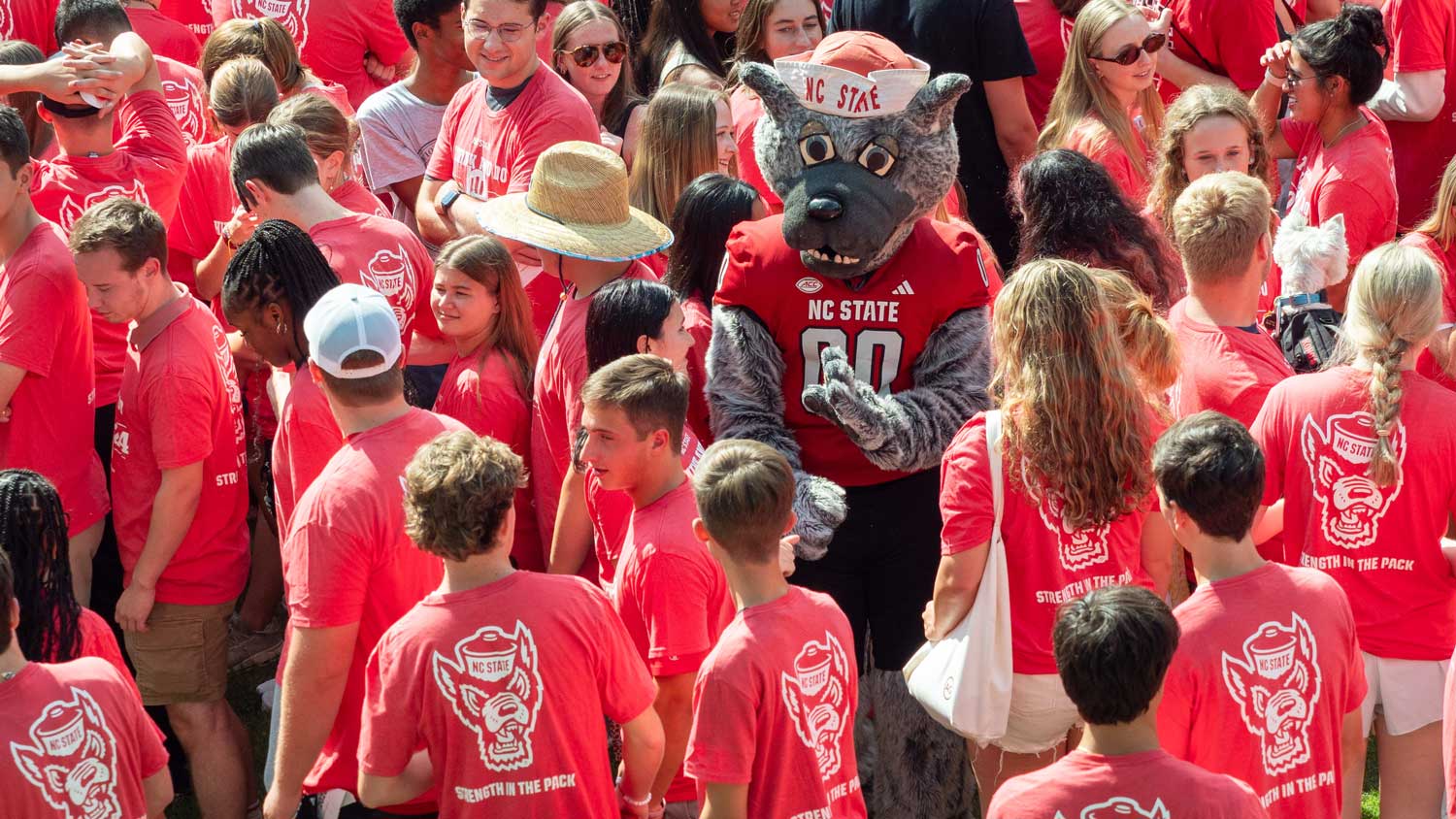 Mr. Wuf surrounded by a large group of NC State students in red T-shirts