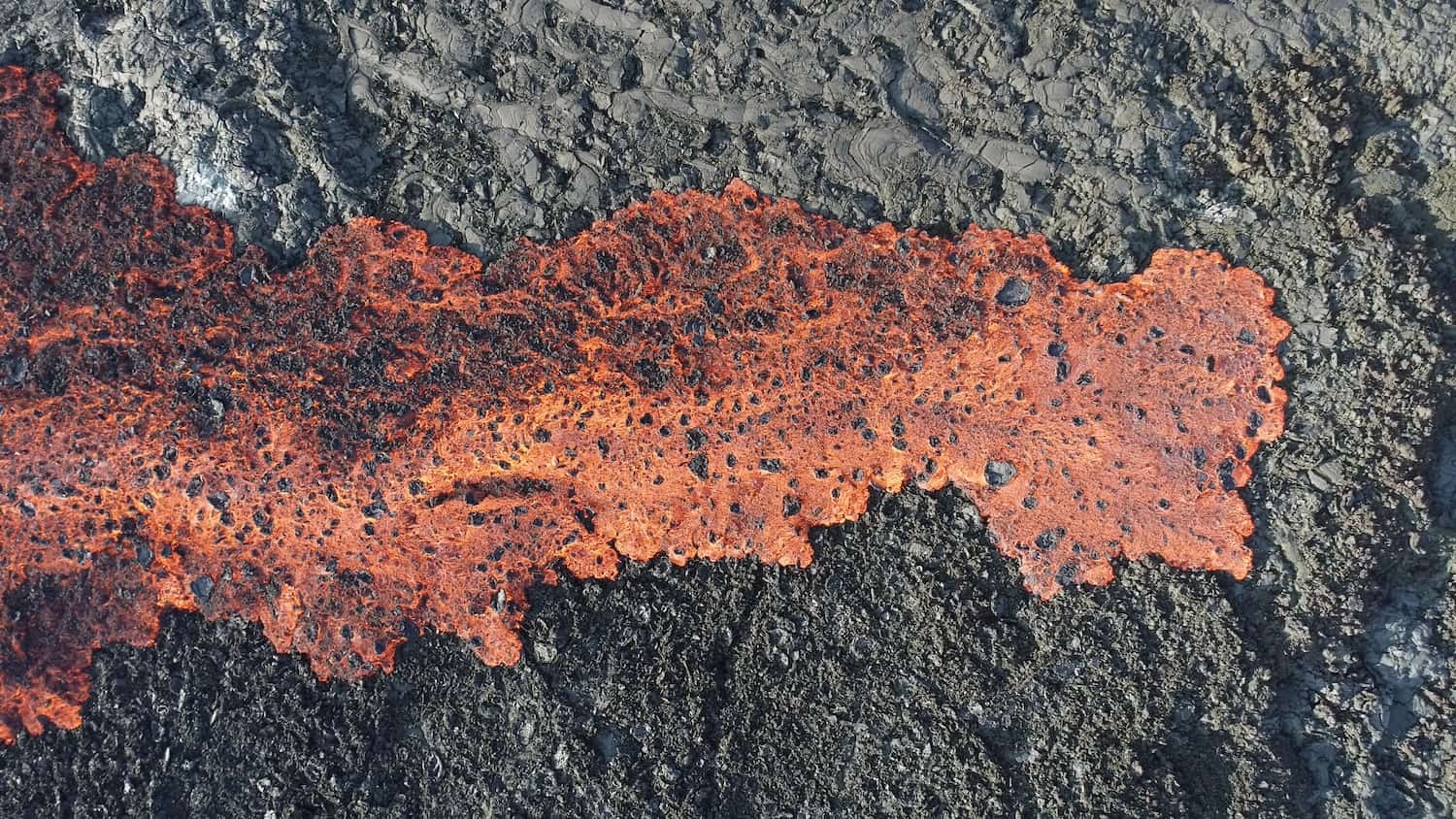 A lava flow creeps through the Iceland landscape